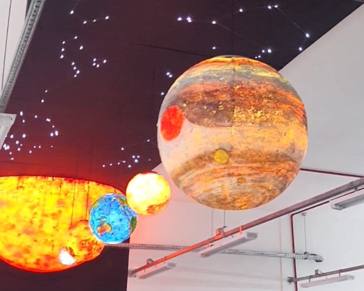 Maquete do sistema solar no teto da biblioteca, com estruturas iluminadas